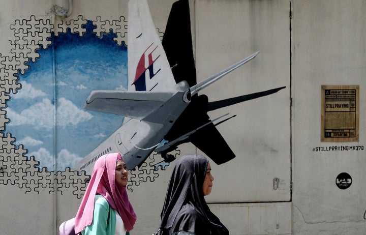 Malaysian women walk in front of a mural of missing Malaysia Airlines MH370 plane. The search, over 120,000 square kilometers of the southern Indian Ocean off Western Australia, is expected to end in three months.