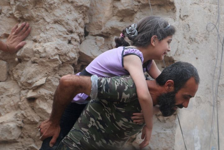 A man carries an injured girl after an airstrike on Aleppo's rebel held Kadi Askar area, on 8 July 