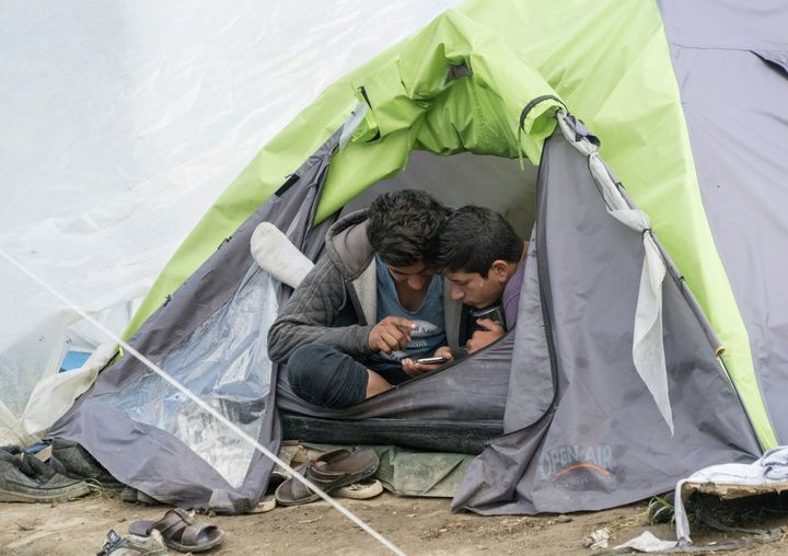 Two men play with a mobile phone at a makeshift camp for migrants and refugees near the village of Idomeni not far from the Greek-Macedonian border on April 25, 2016. Some 54,000 people, many of them fleeing the war in Syria, have been stranded on Greek territory since the closure of the migrant route through the Balkans in February. / AFP / JOE KLAMAR (Photo credit should read JOE KLAMAR/AFP/Getty Images)