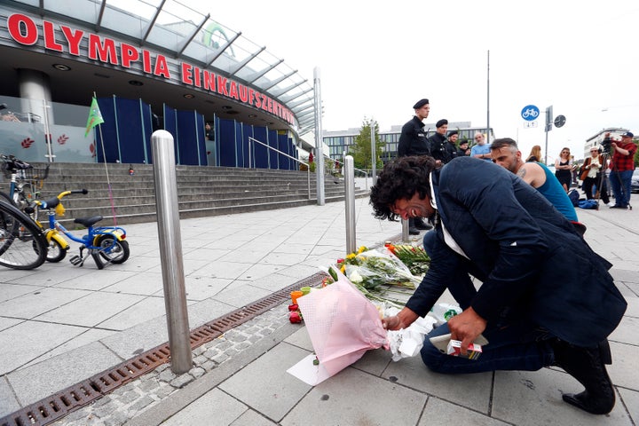 A man places flowers outside the Olympia shopping mall in Munich, where a German-Iranian teenager killed nine people on