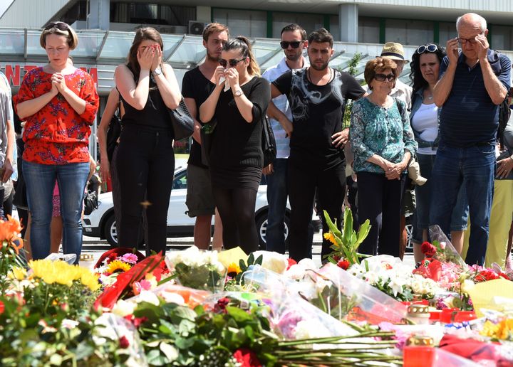 People mourn at a memorial of candles and flowers on July 24, 2016 in front of the Olympia Einkaufszentrum shopping centre in Munich