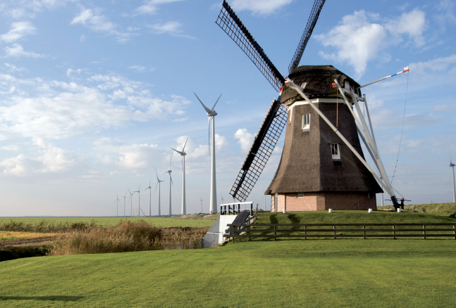 The 156 MW Westereems wind park in Eemshaven is Netherlands' largest onshore wind farm. Its modern turbines are shown here stretching toward the horizon. In the foreground is a traditional Dutch windmill nicknamed Goliath, built in 1897 to drain the Eemspolder. 