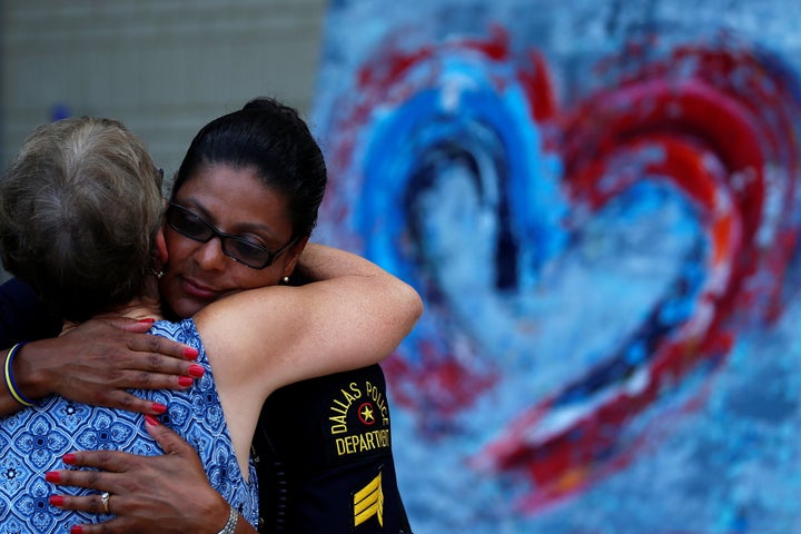 A woman hugs a Dallas police officer at a makeshift memorial at police headquarters following the multiple police shootings in Dallas, Texas.