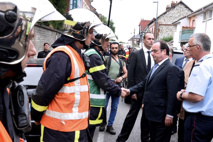 Hollande shakes hands with French firemen as he arrives in Saint-Etienne-du-Rouvray
