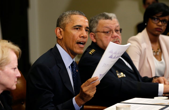 President Barack Obama holds up a copy of the report by the Task Force on 21st Century Policing at the White House in Washington March 2, 2015.