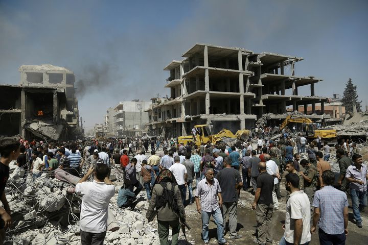 Syrians gather at the site of a bomb attack in Syria's northeastern city of Qamishli.