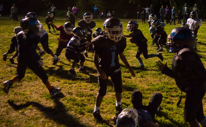 Young D.C. Pop Warner League football players run plays during practice after a visit from former NFL player Cato June, who spoke with them about sportsmanship and proper tackling techniques at Simon Elementary School on September 17, 2013 in Washington, D.C. The visit by the former NFL player and Anacostia coach was part of an initiative with Heads Up Football to teach kids safety and proper tackling techniques at an early age.