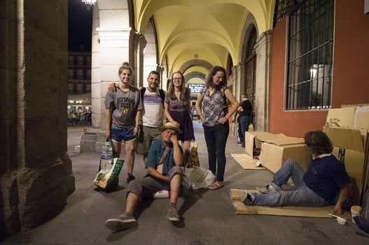 Lagarder and Nico, a homeless man, pose for a photo with English women who visit the Plaza Mayor every week to distribute food and drinks to the homeless.