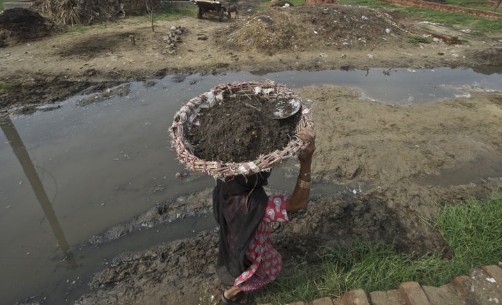 60 year old manual scavenger Kela carrying a basket of human excrement her head after cleaning toilets in Nekpur village, Mur
