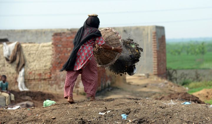 In this picture taken on August 10, 2012, 60 year old manual scavenger Kela dumping a basket of human excrement after cleaning toilets in Nekpur village, Muradnagar in Uttar Pradesh, some 40 kms east of New Delhi. Already illegal under a largely ineffective 1993 law, the government has promised to have another go at stamping out the practice with new legislation set to come up in the last parliament session of the year, which opens this week. AFP PHOTO/ Prakash SINGH