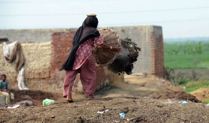 In this picture taken on August 10, 2012, 60 year old manual scavenger Kela dumping a basket of human excrement after cleanin