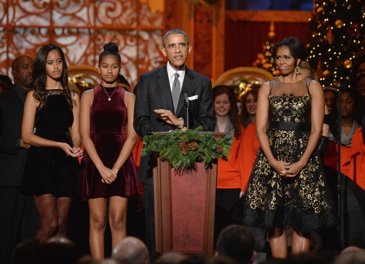 (L-R) Malia Obama, Sasha Obama, President Barack Obama, and First Lady Michelle Obama speak onstage at TNT Christmas in Washington in 2014.