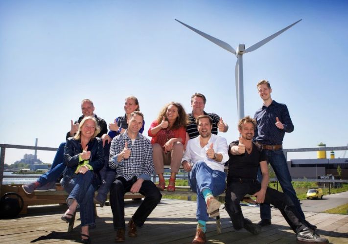 <em>NDSM Energy cofounders at NDSM Wharf in 2013. NDSM Energy aims to provide the NDSM Shipyard with sustainable and environmentally friendly energy by cooperatively developing renewable energy projects. Engineer Martijn Pater, NDSM Energy Executive Director is third from right. Eva de Klerk, prime mover behind the effort to repurpose the former NDSM shipyard complex, is in the center.</em>