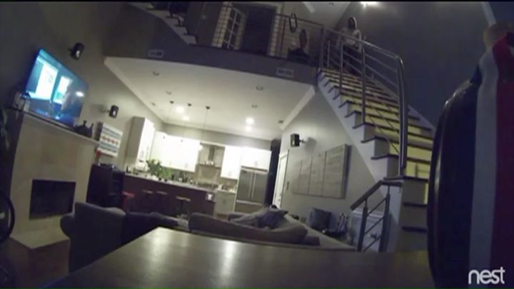 Surveillance video taken early Monday morning shows a man standing on the staircase as the couple sleeps on a couch below.