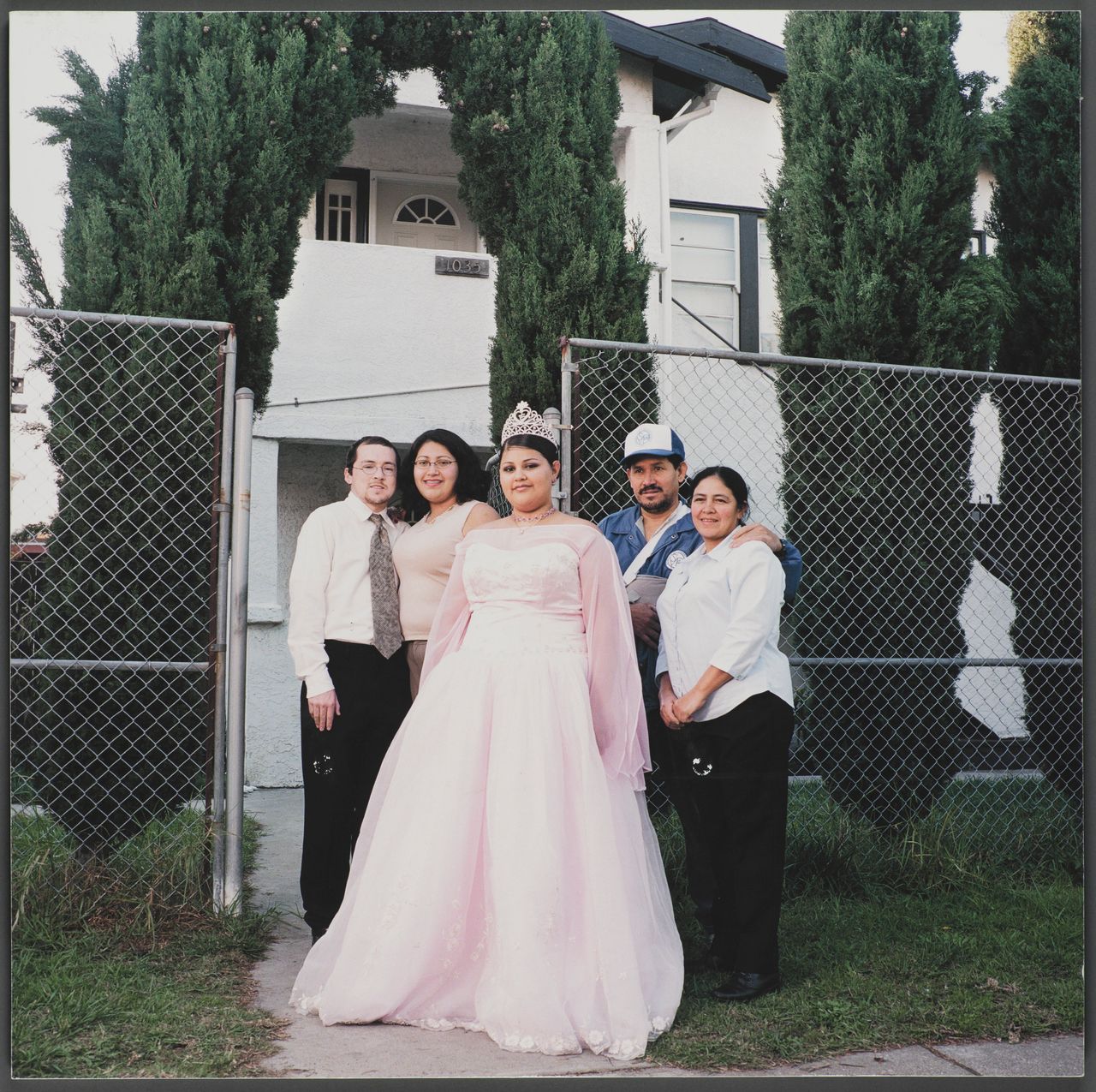 "1103 Chester Street," 16x16 giclee print, 2003, by Julie Placensia. The Polio Family, originally from El Salvador, commissioned this photograph on the day of Nancy’s quinceañera. The family continues to live in the duplex, and rents out the bottom portion to extended family.