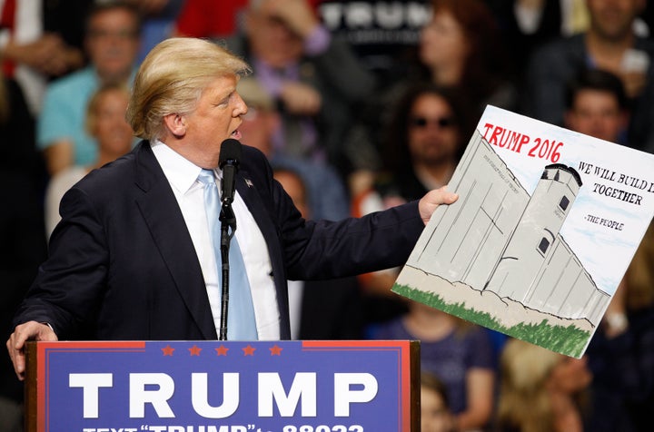 Donald Trump holds a sign supporting his plan to build a wall between the United States and Mexico that he borrowed from a member of the audience at his campaign rally in Fayetteville, North Carolina March 9, 2016.