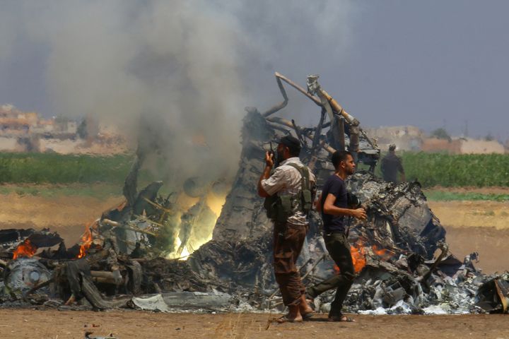 Men inspect the wreckage of a Russian helicopter that was shot down north of Syria's rebel-held Idlib province.