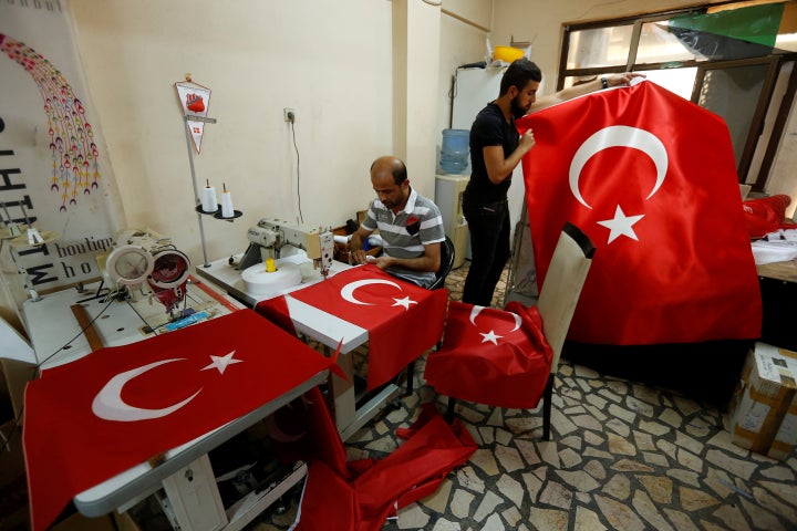 Workers make Turkish flags at a small flag factory in Istanbul, Turkey. The Turkish prime minister says the government takeover of factories and shipyards won't weaken the military.