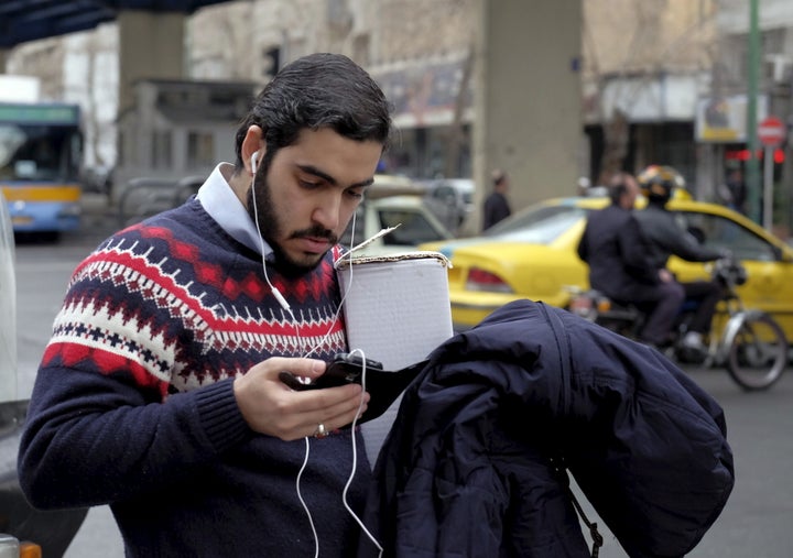 A man checks his mobile phone at a sidewalk in Tehran February 20, 2016.