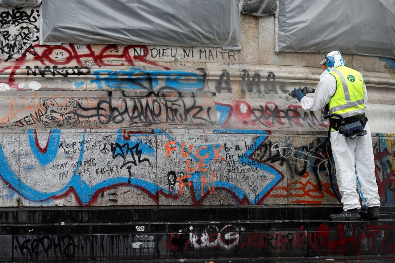 A city employee cleans graffiti off the statue of Place de la Republique in Paris, on August 2, 2016