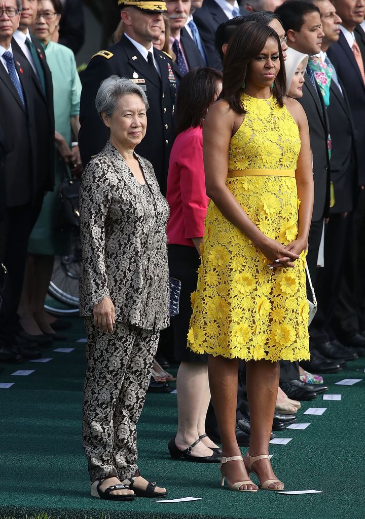 Michelle Obama wears a vibrant yellow Naeem Khan dress while standing with Ho Ching, wife of Singapore Prime Minister Lee Hsien Loong, during an arrival ceremony at the White House in Washington, D.C.