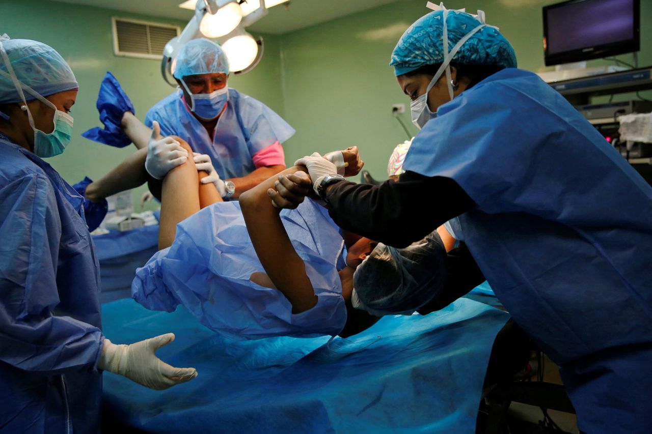 Medical personnel move a woman during her sterilization surgery.