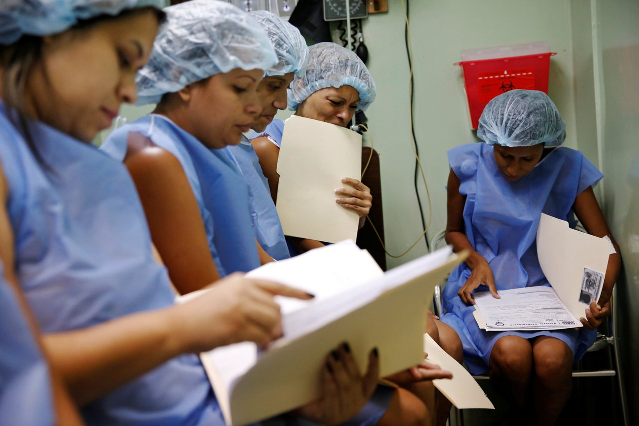 Women read files while awaiting sterilization at the hospital.