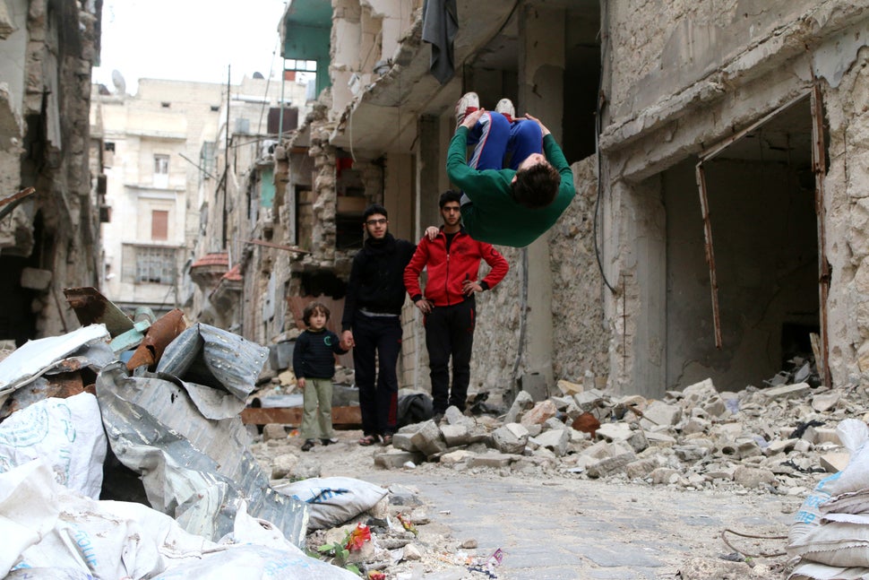 Al-Sawas performs gymnastic moves near damaged buildings in Bustan al-Qasr on March 26, 2016. He trains whereever h
