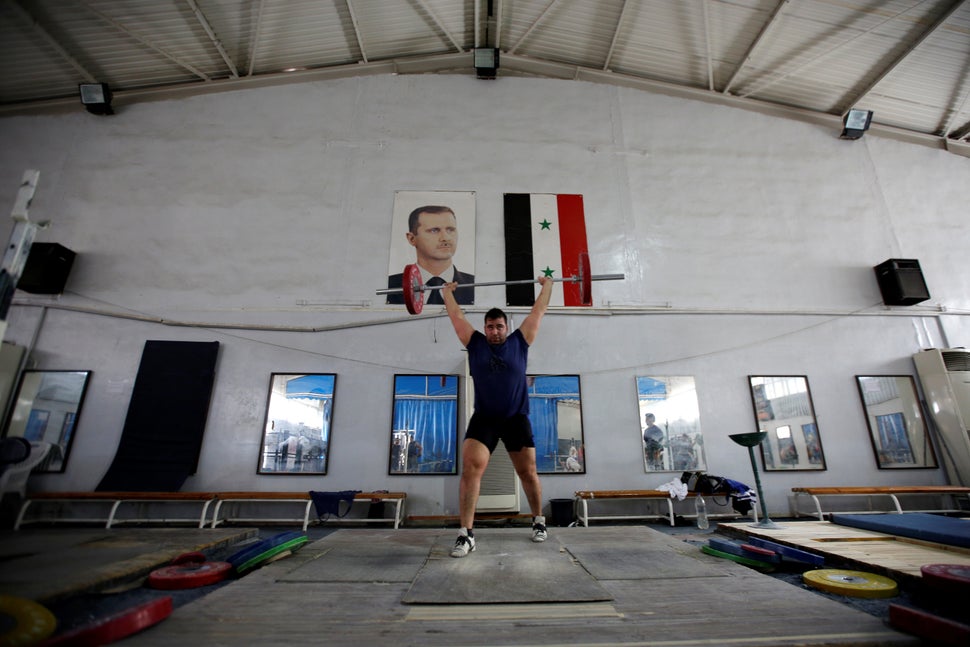 Syrian weightlifter, Man Asaad, trains for the Rio Olympics near a picture of Syrian President Bashar al-Assad and a Syrian n