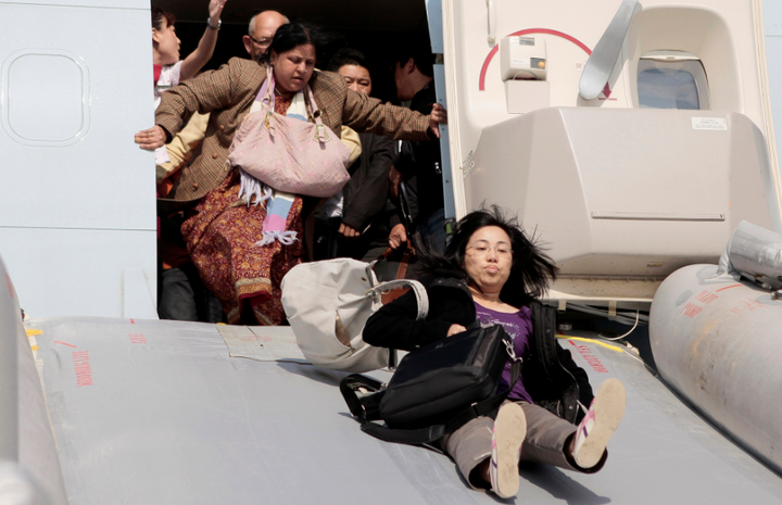 Passengers flee a Cathay Pacific Boeing 747 with their luggage