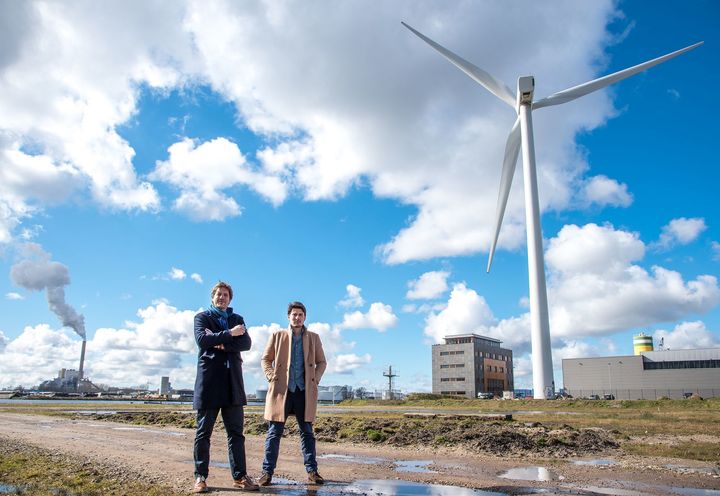<em>NDSM Director Martijn Pater (left) and NDSM Projects Manager Keijen van Eijk (right) stand at the NDSM Wharf. At right is a two megawatt Vestas V80 wind turbine, one of the last turbines built within Amsterdam before the province of North Holland’s restrictive wind siting regulations took effect in 2011. At far left is a coal power plant with a 175 meter tall smokestack. </em>