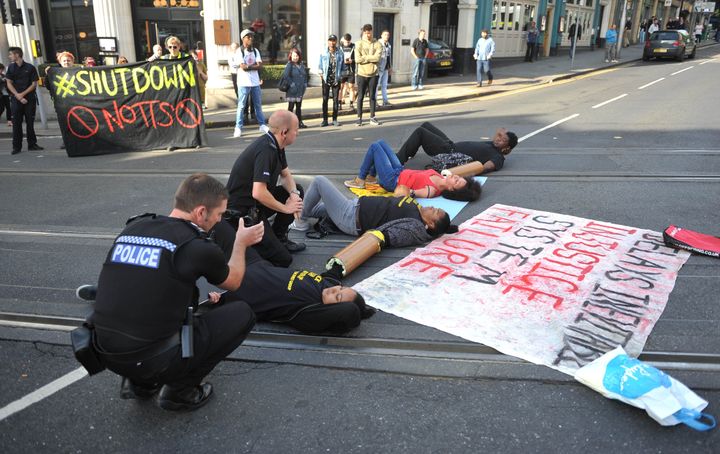 Police officers talk with protesters in Nottingham city centre after activists blocked the tram tracks.