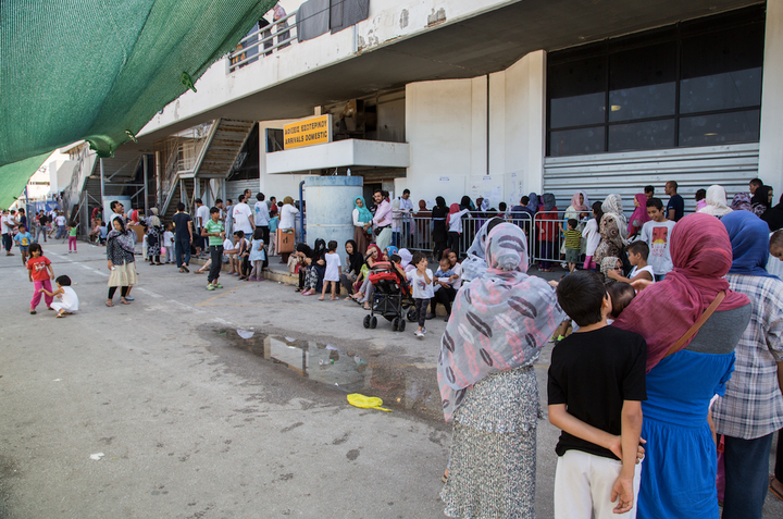 Refugees wait in line for vaccines. 