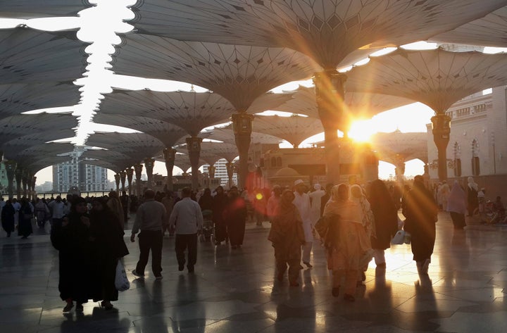 The sun rises as Muslims walk in front of al-Masjid al-Nabawi, the Mosque of Prophet Mohammad, after their early morning pray