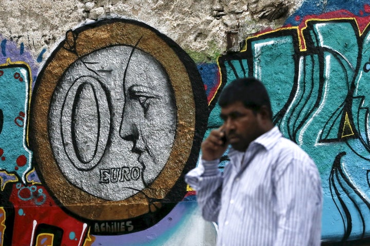 A man walks past a graffiti by Greek street artist Achilles, depicting a zero Euro coin in Athens on June 26, 2015.