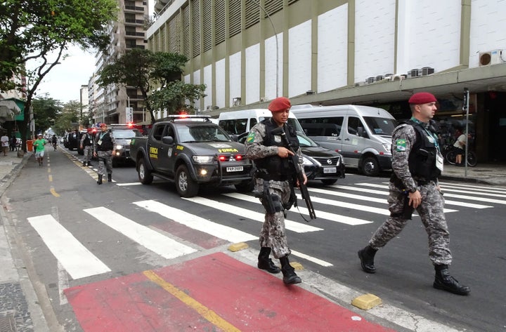 Security personnel walk along Copacabana beach.