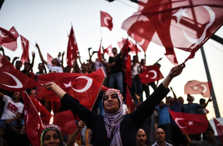 Demonstrators wave Turkish national flags as they stand in front of giant screens on August 7, 2016.