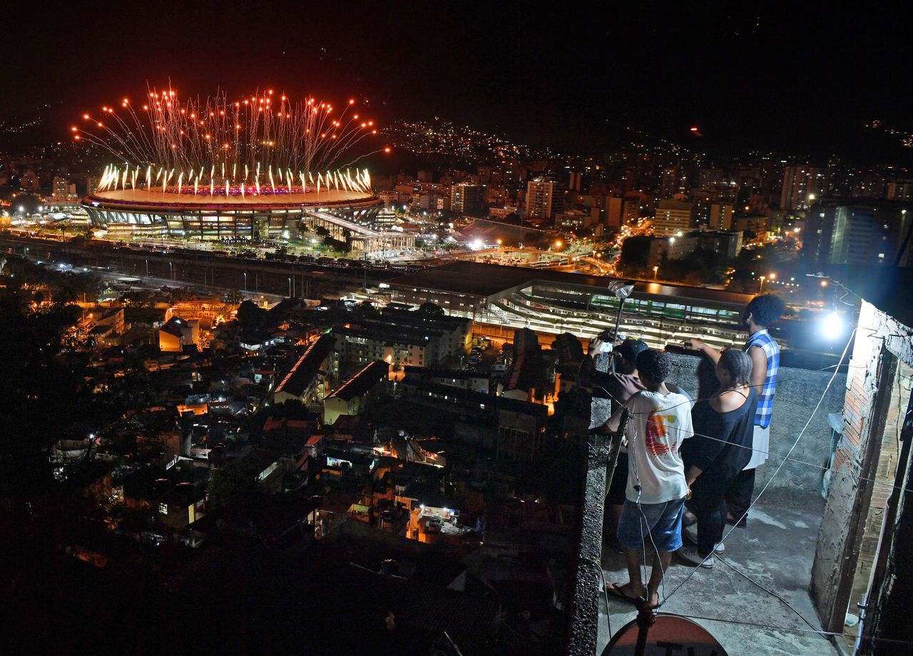 People watch fireworks exploding over the Maracana stadium from a terrace in the favela Mangueira during the opening ceremony of the Rio 2016 Olympic Games.