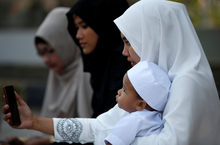 A woman takes a photograph following Eid al-Fitr prayers to mark the end of the holy fasting month of Ramadan in Jakarta, Indonesia July 6, 2016.