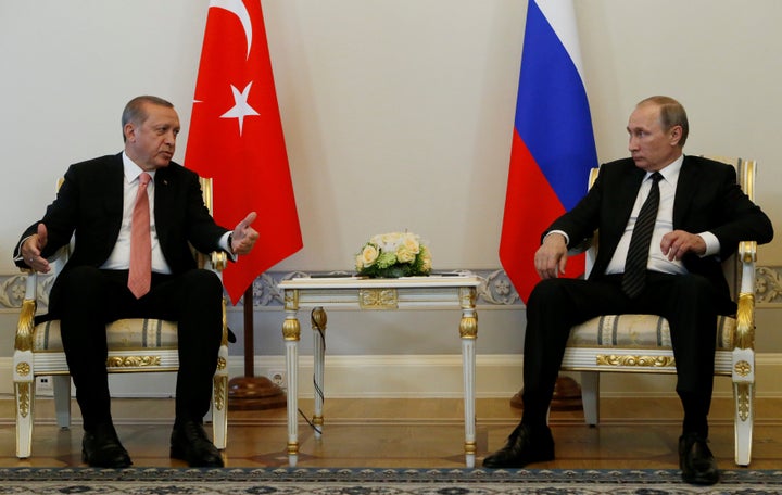 Turkish President Tayyip Erdogan speaks to Russian President Vladimir Putin (R) during their meeting in St. Petersburg, Russi