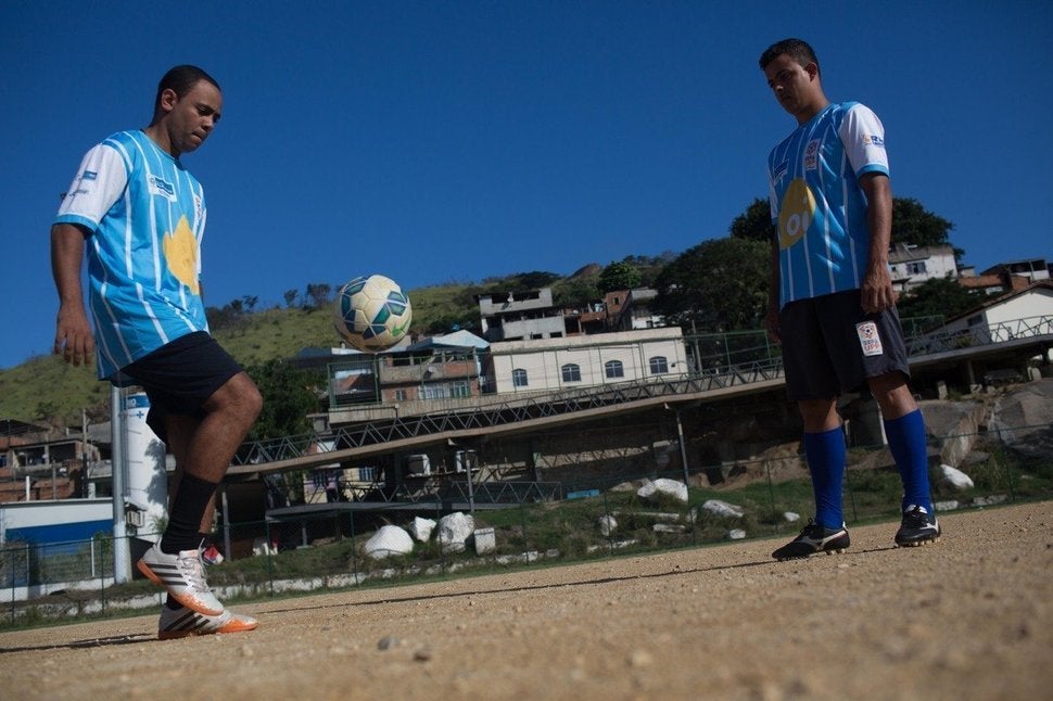 A policeman and a resident of the slum complex of Mangueirinha pass a soccer ball in Morro dos Macacos, a hillside area in no