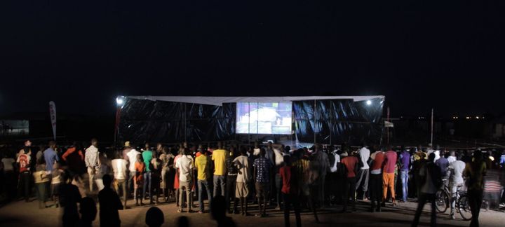 Refugees at the camp gather in front of a screen to watch the games