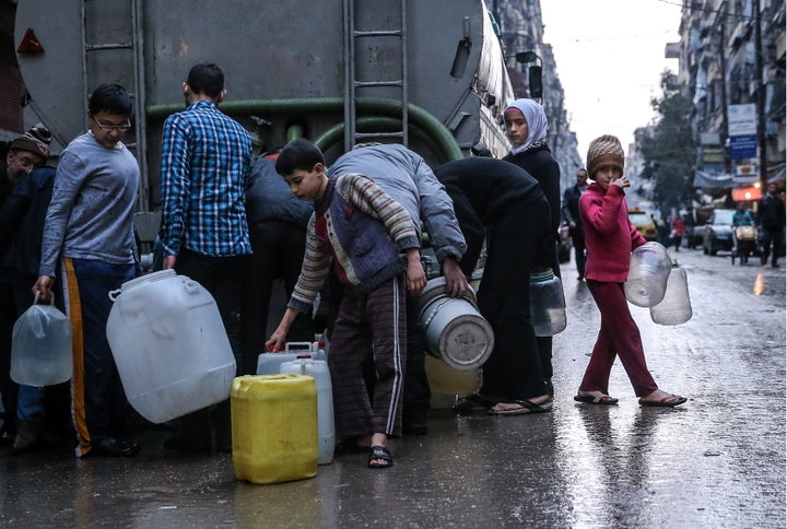 SYRIA. MARCH 5, 2016. Children fill containers with drinking water from a tanker in Salah al-Din, Aleppo. Valery Sharifulin/TASS (Photo by Valery Sharifulin\TASS via Getty Images)