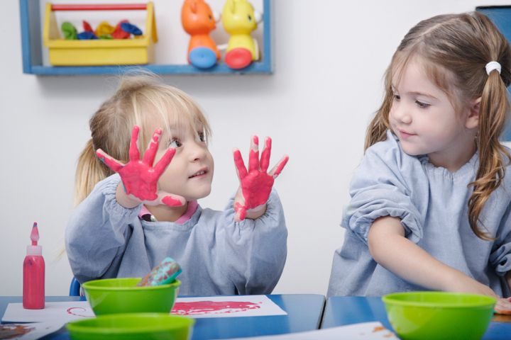 Girls finger-painting in classroom Floresco Productions via Getty Images
