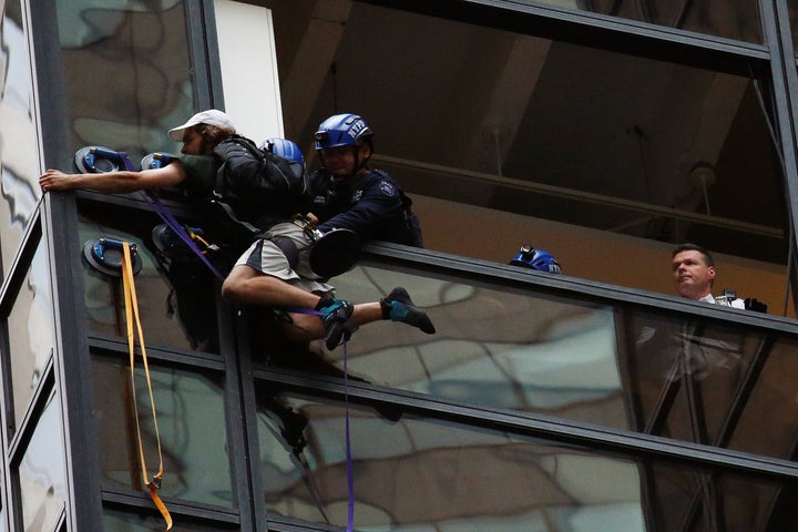 Officers from the NYPD embrace a man to stop him from climbing the outside of Trump Tower in New York, U.S., August 10, 2016.