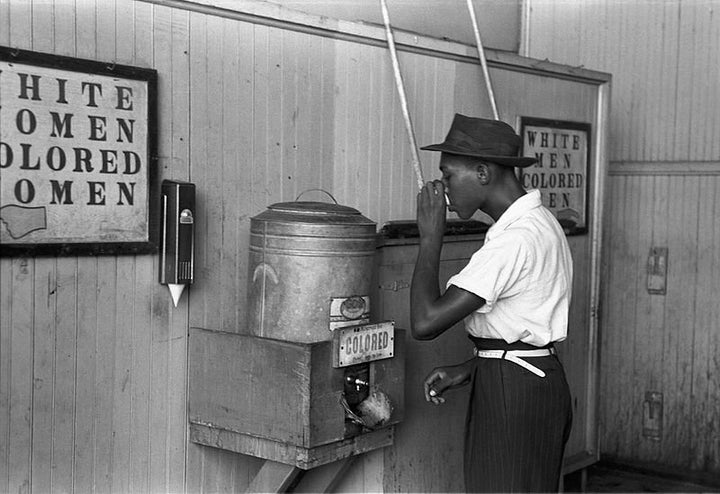 "Colored" drinking fountain from mid-20th century with african-american drinking (Original caption from July 1939: "Negro drinking at "Colored" water cooler in streetcar terminal, Oklahoma City, Oklahoma").