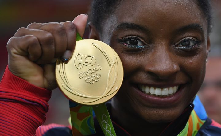 Gymnastics champion Simone Biles poses for photographs with her gold medal at the 2016 Olympic Games in Rio de Janeiro, Brazil.