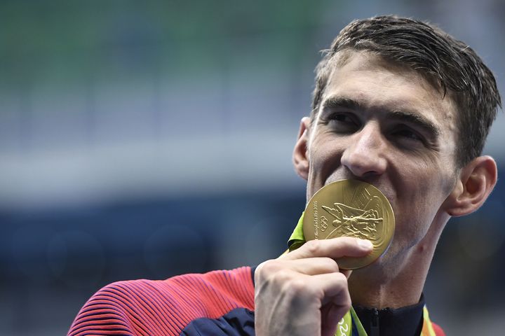 Michael Phelps celebrates with his gold medal during the podium ceremony for the Men's 4x200m Freestyle Relay Final.