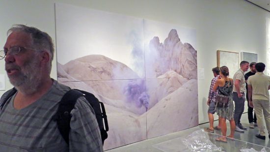Artist Galen Brown stands before work by Timothy Conder, Nick Larsen, and Omar Pierce in Tilting the Basin.