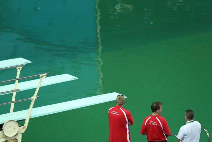 Officials look at the Olympic diving pool on Tuesday. It's definitely green.